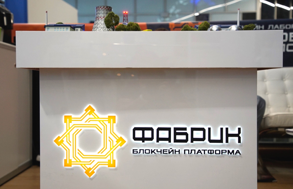 Стенд платформы Фабрик: подсвеченный логотип блокчейн-платформы и верхняя часть промышленного макета.