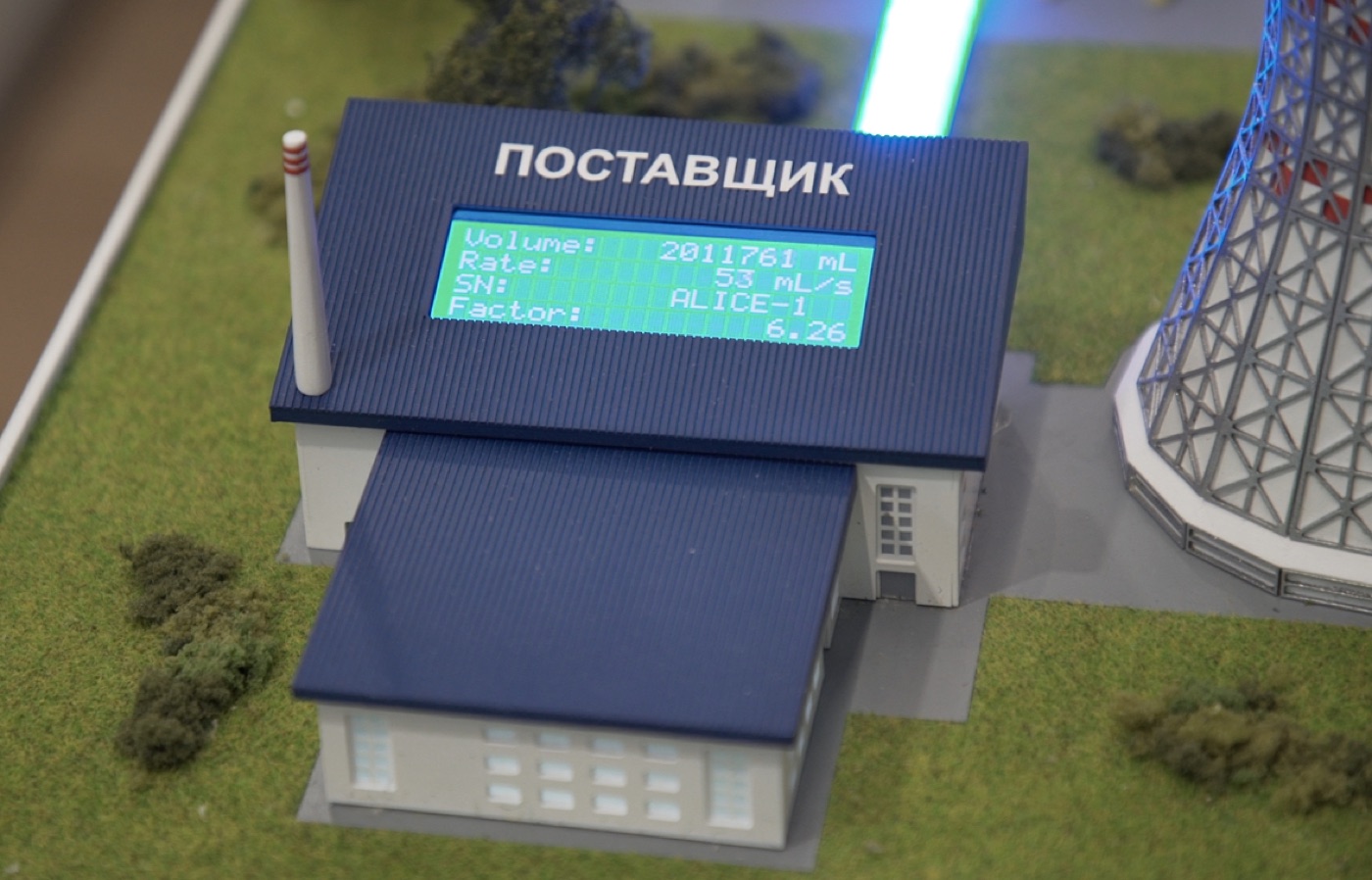 Крупный план здания Поставщик на макете с экраном телеметрии: volume, rate, sensor, factor.